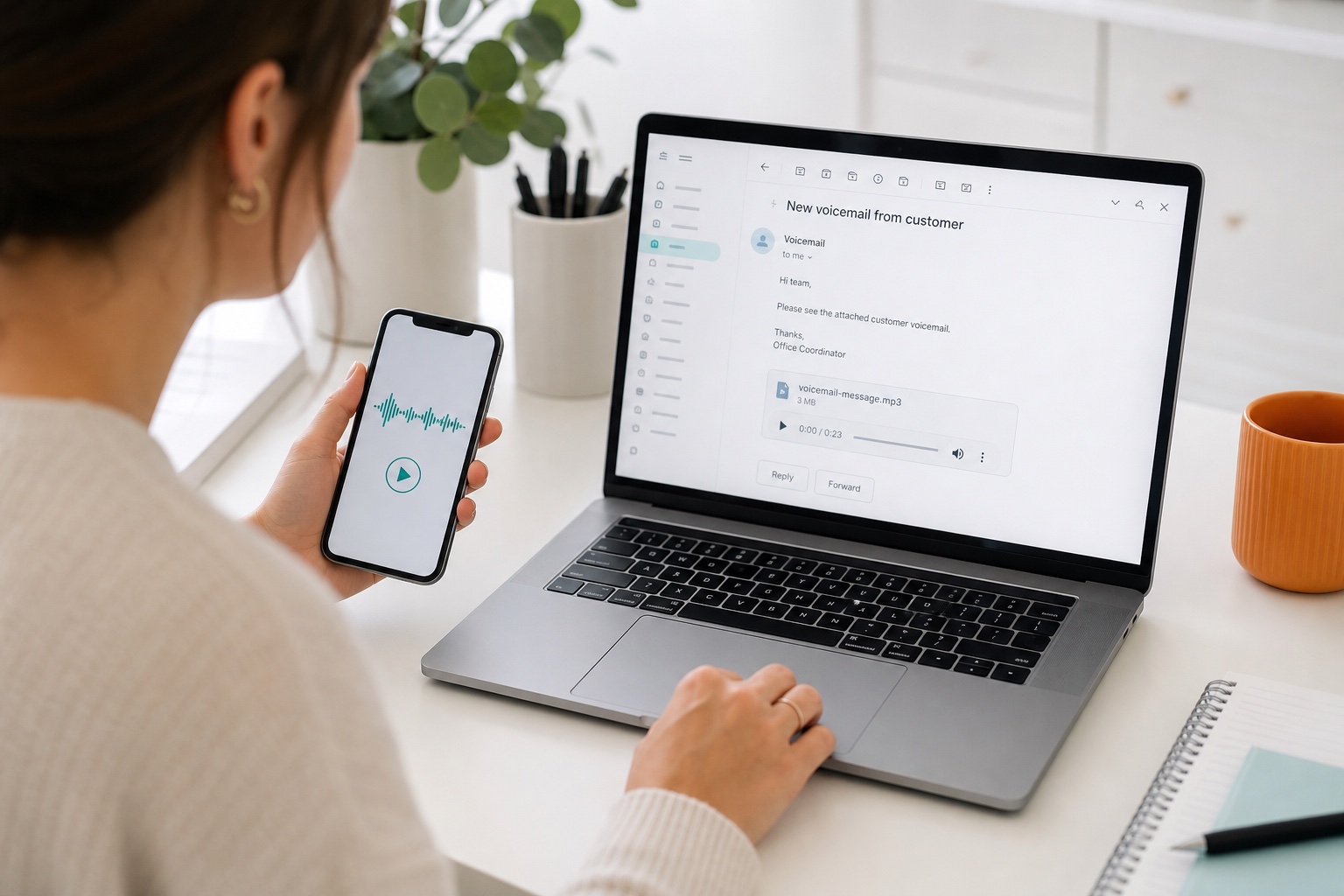 An office coordinator reviews a voicemail on a smartphone beside the matching audio message in an email inbox.